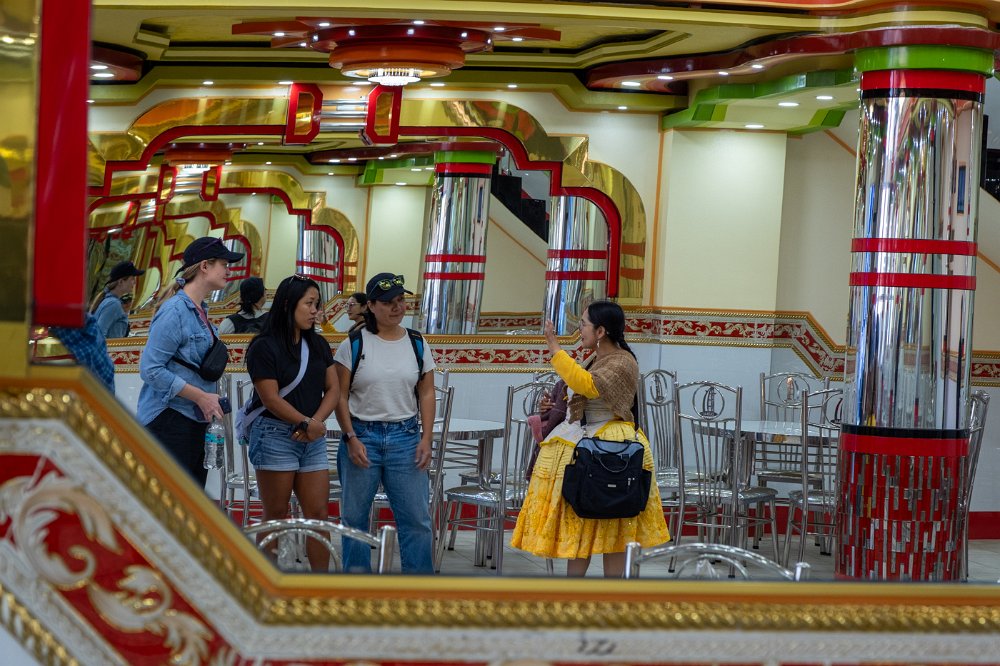 Aracely speaking with guests in an ornate interior space in La Paz.